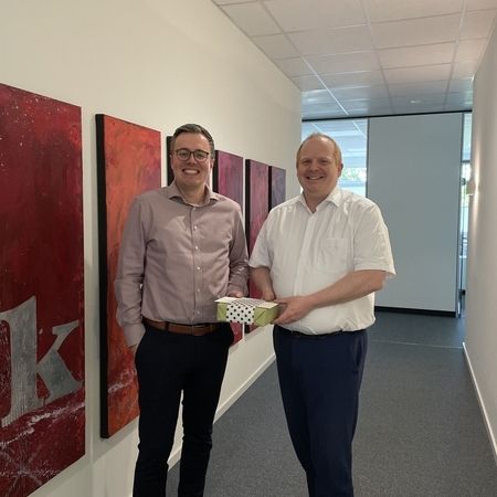 Zwei Männer mit Geschenk im Büroflur mit Kunst