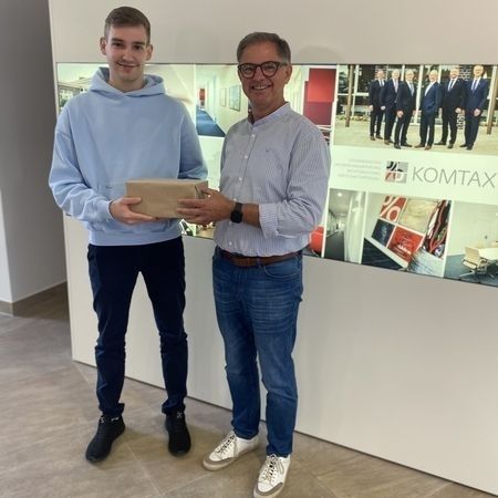 Junger Mann erhält Geschenk von älterem Mann bei KOMTAX