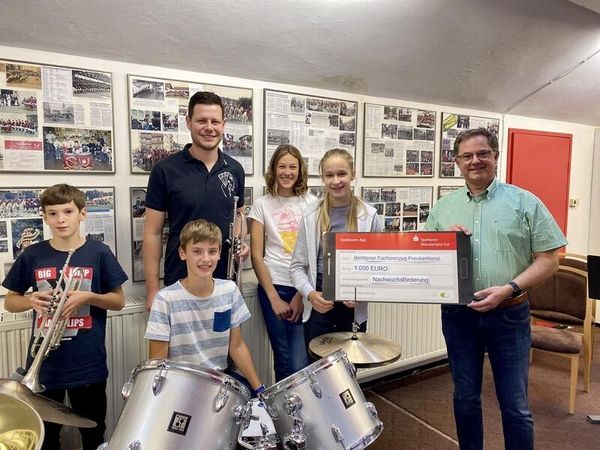 Gruppe mit Kindern und Erwachsenen bei Spendenübergabe mit großem Scheck