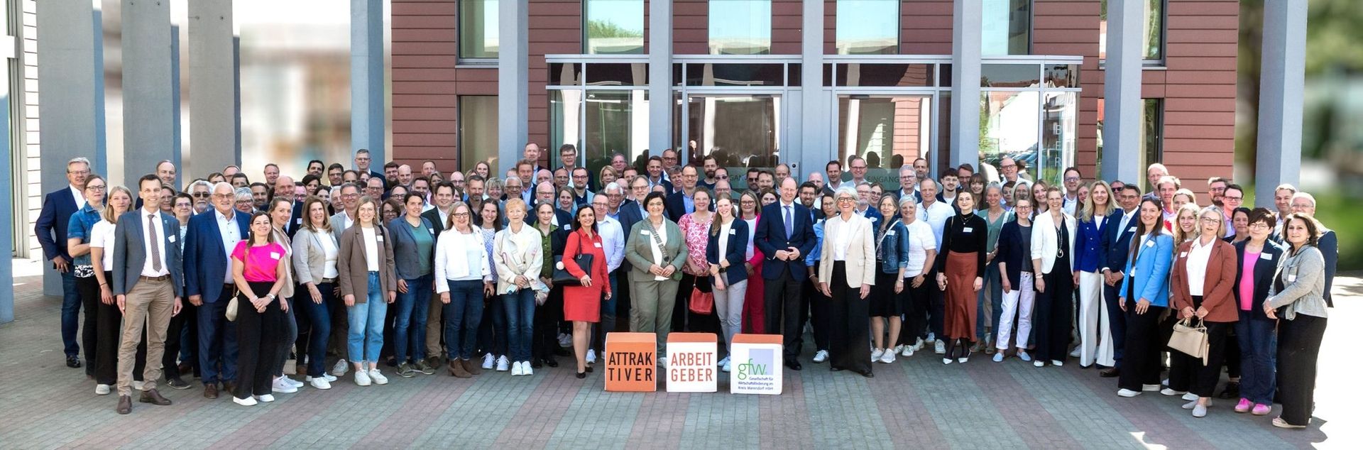 Große Gruppe vor Gebäude mit Auszeichnung Attraktiver Arbeitgeber